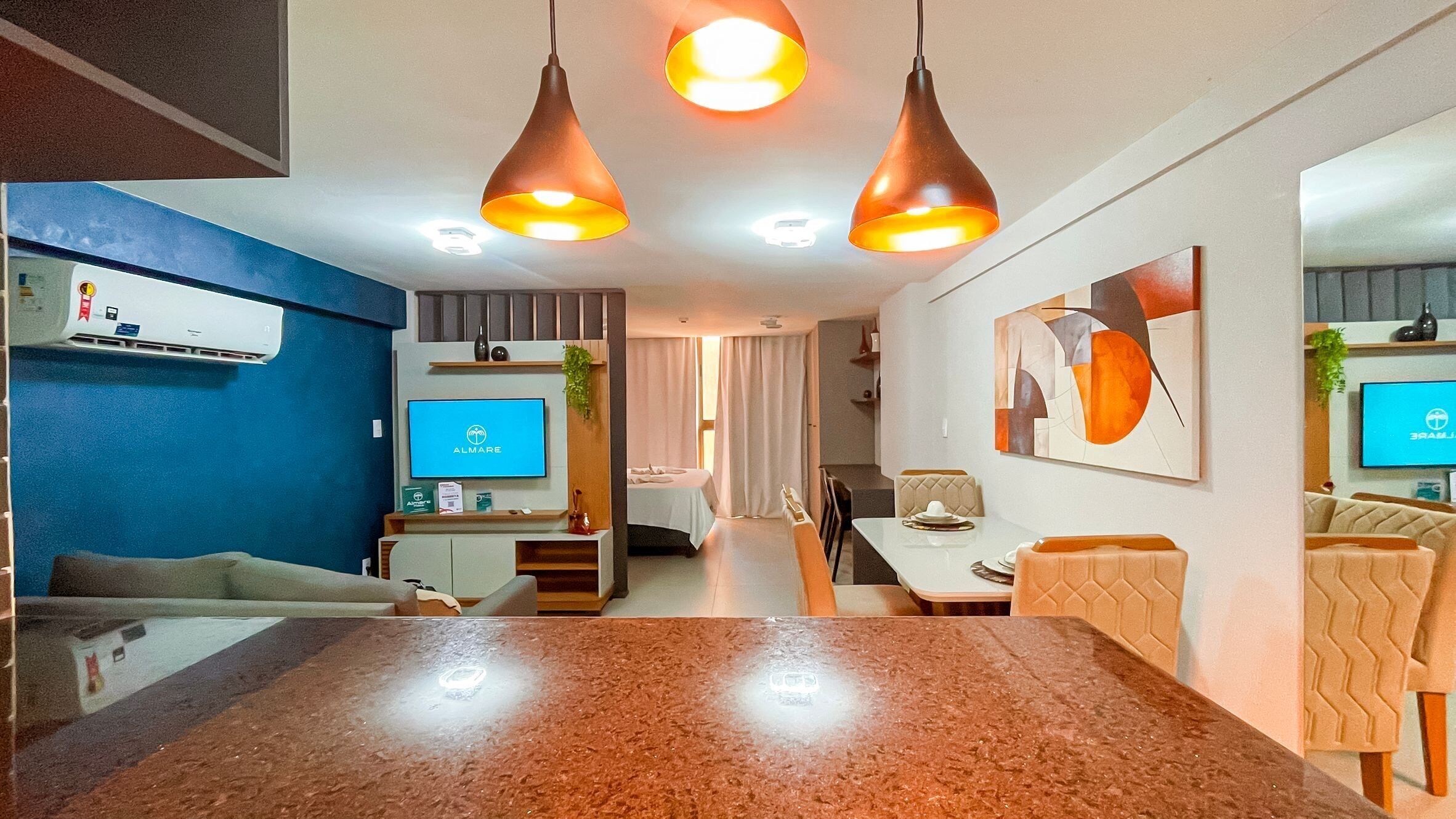A modern hotel room with a dining area, a TV, and a large abstract painting on the wall.