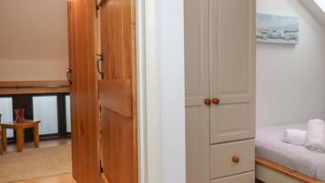 Une chambre avec une armoire en bois, un lit avec une literie blanche et un tableau accroché au mur.
