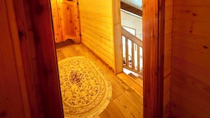 Een houten interieur met een rond tapijt, houten wanden en een balkon.