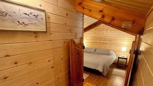 Een gezellig houten slaapkamer met een bed, een nachtkastje en een lijst met kunstwerk aan de muur.