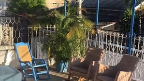 A covered outdoor seating area with two rocking chairs and a wooden table. - HOSTAL CASA SANTORINI (Cartagena)