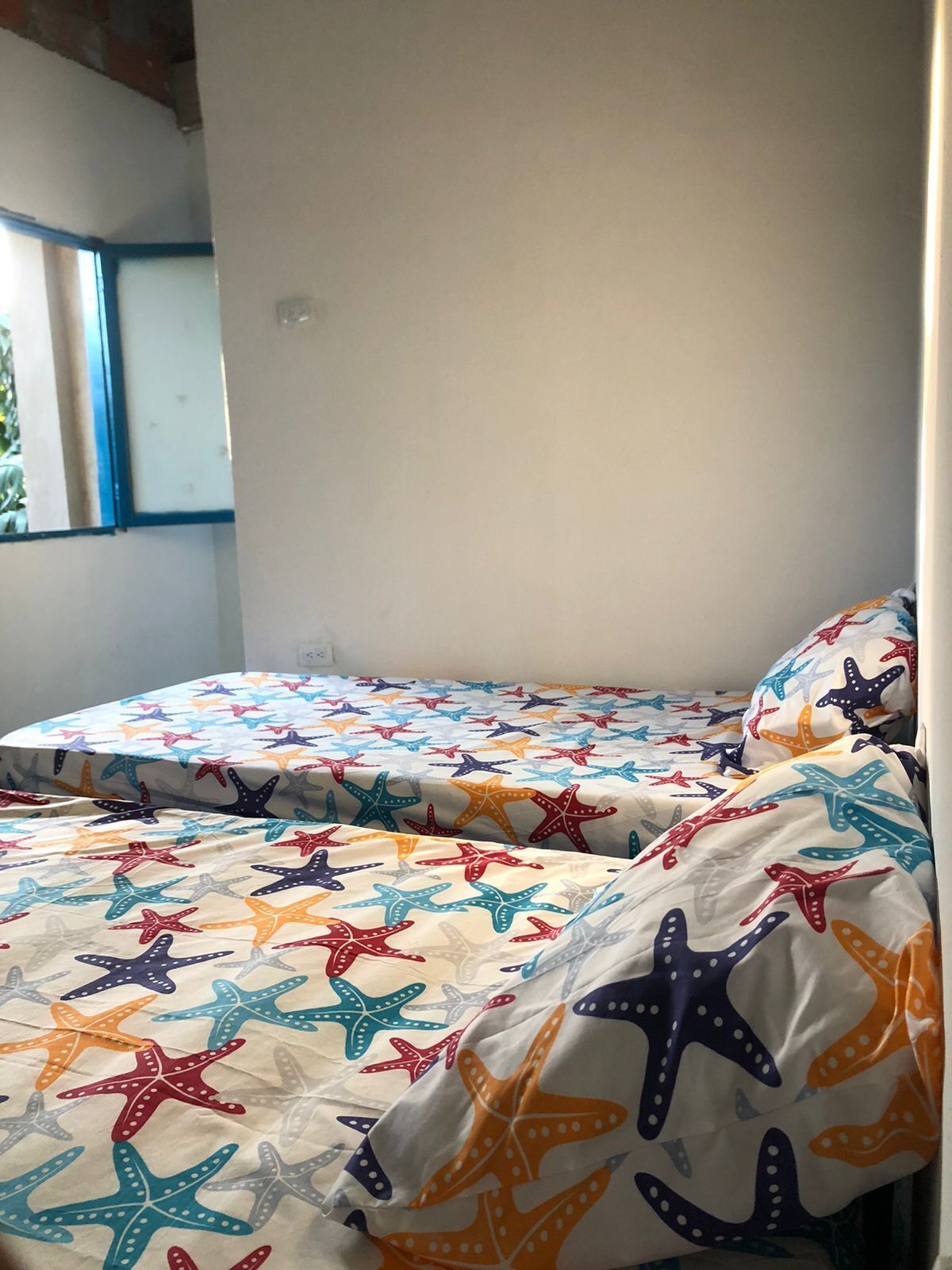 Una habitación con dos camas, cada una con un edredón estampado con motivos de estrellas de mar.
