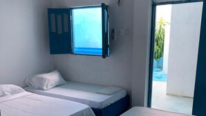 A room with two beds, a window, and an air conditioning unit. - HOSTAL CASA SANTORINI (Cartagena)