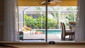 Une piscine entourée d’une enceinte en verre, bordée d’une végétation luxuriante et agrémentée de meubles en osier.