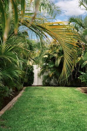 A well-maintained garden with a variety of tropical plants and a neatly trimmed lawn.