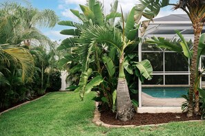 A lush garden with palm trees and a pool area. - Heated Pool House w/ Game Room, Near Englewood (Englewood)