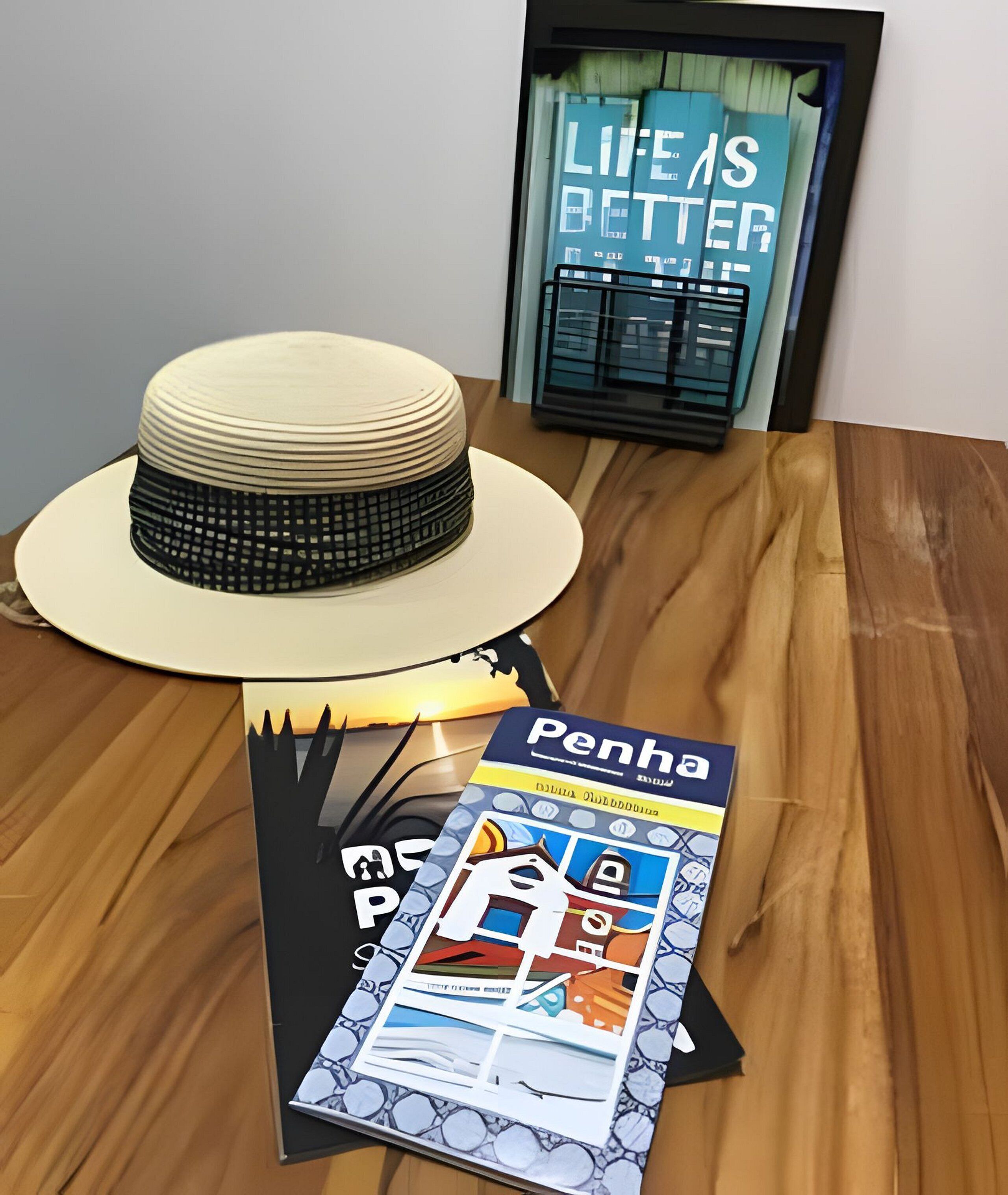 A hat on a table with a magazine titled "Penha" and a framed picture with the text "LIFE'S BETTER".