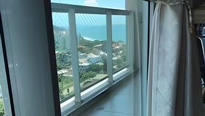 A room with a large window overlooking a scenic landscape. - Velutti Pérola do Mar - Penha - SC (Penha)
