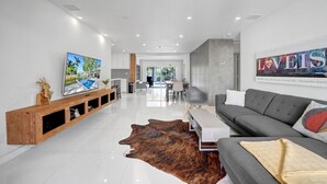 Un salon moderne avec un canapé gris, une console en bois, un grand tableau et un tapis en peau de vache.
