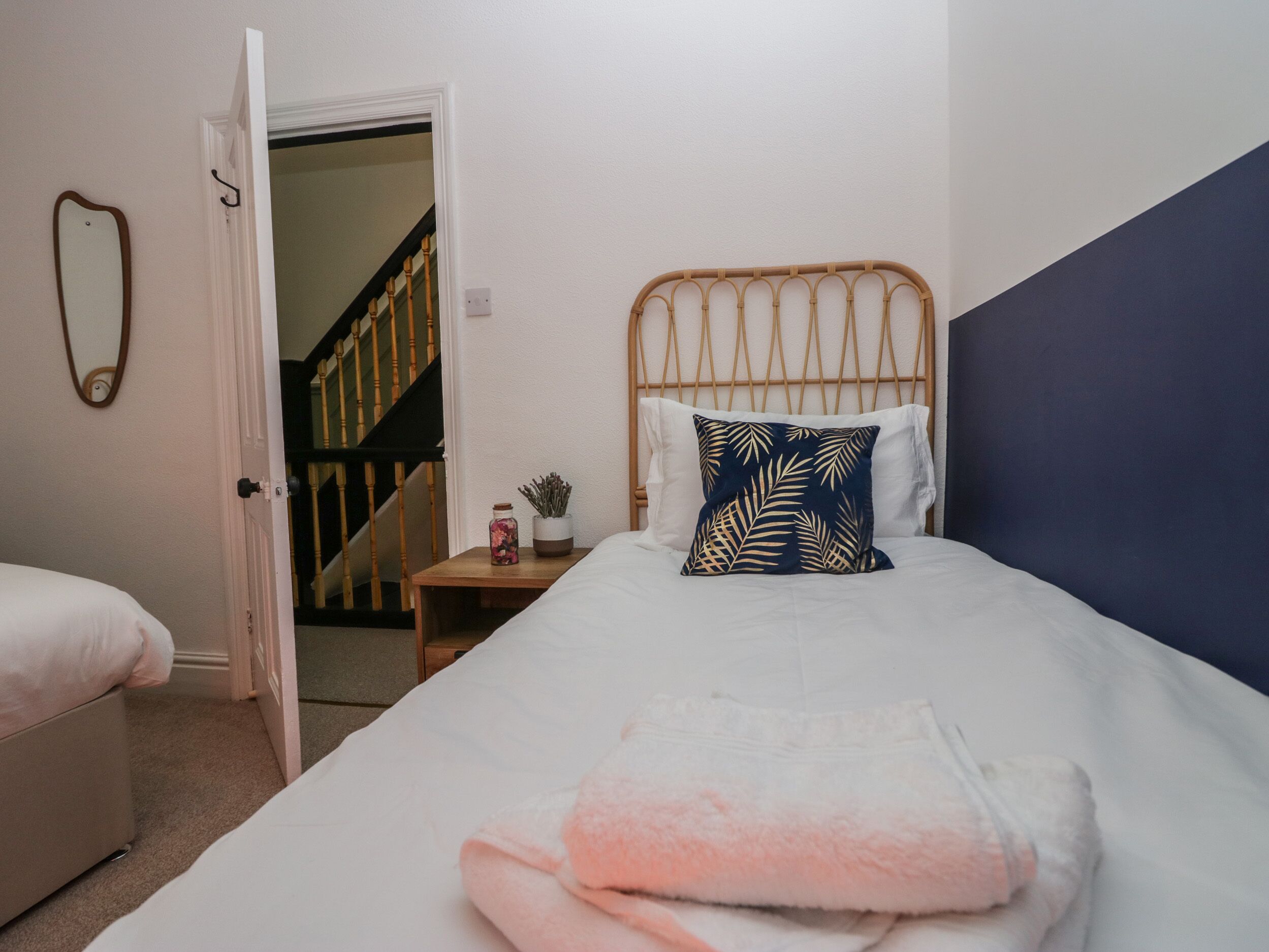 Un dormitorio con cama, mesita de noche, espejo y escalera.