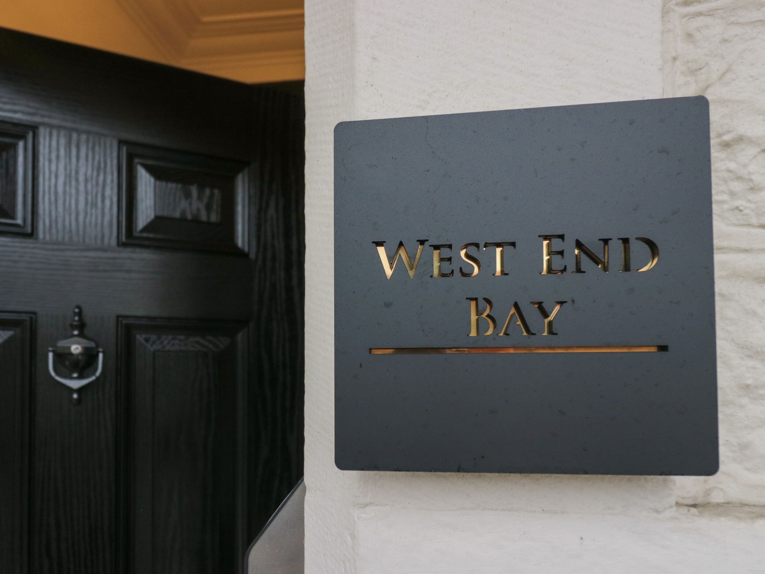 A sign with "WEST END BAY" in gold lettering on a dark background.