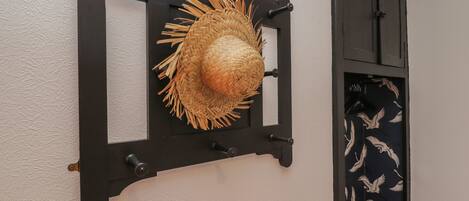 A wall-mounted hat rack with a woven straw hat.
