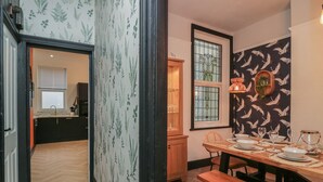 Un comedor con una mesa de madera dispuesta para cuatro personas, un banco y una ventana con vistas al exterior.