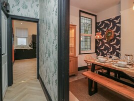 A dining area with a wooden table set for four, a bench, and a window with a view of the outside.