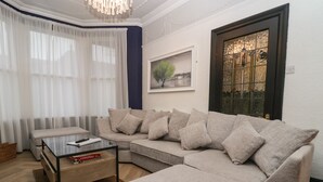 Una sala de estar con un sofá seccional, una mesa de centro de vidrio y un cuadro en la pared.
