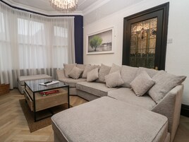 A living room with a sectional sofa, a glass coffee table, and a framed picture on the wall.