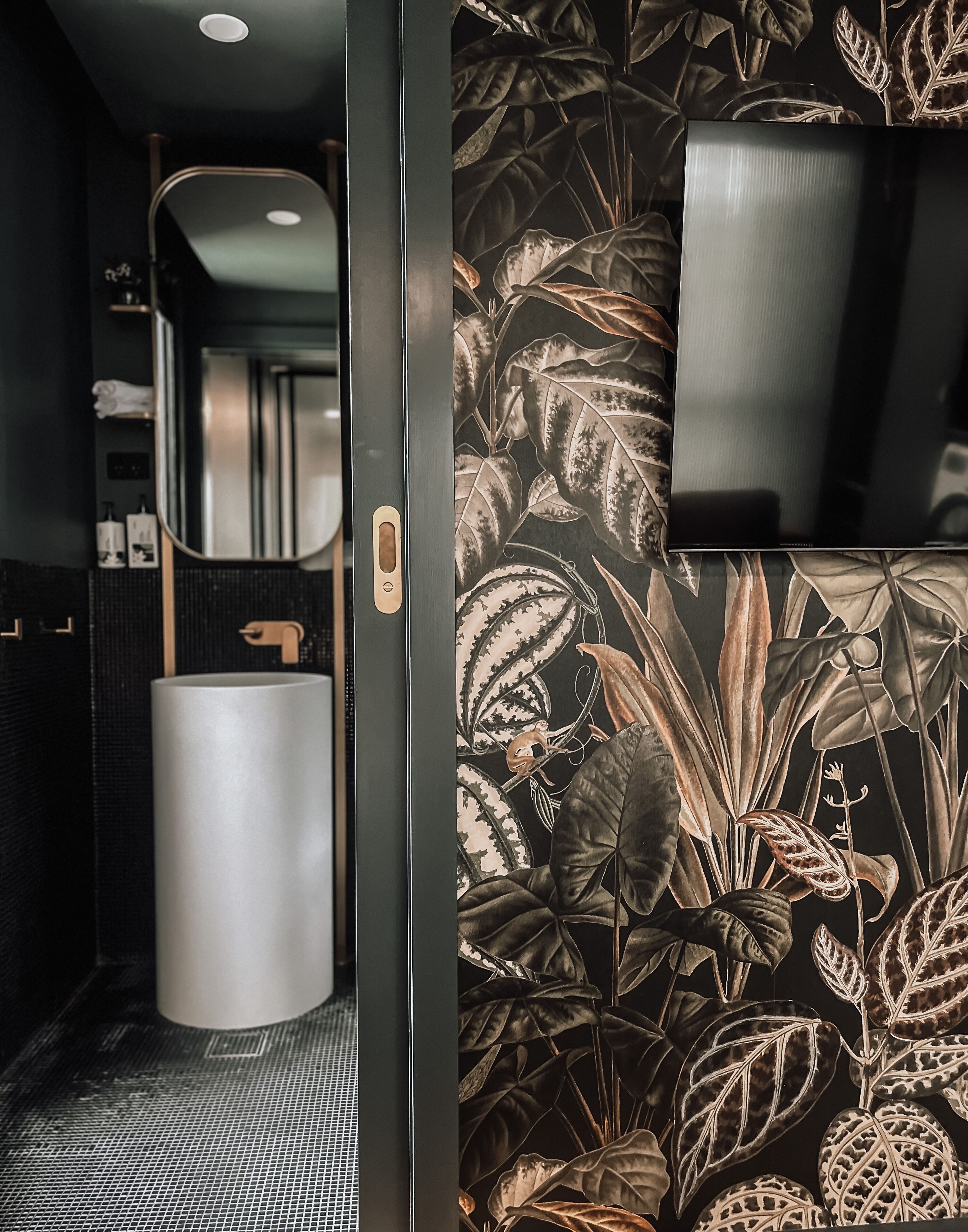 Une salle de bain moderne avec un grand miroir, un lavabo et un espace douche.
