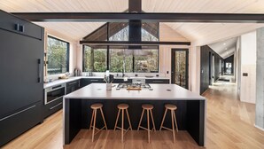 Een moderne keuken met een groot schiereiland, barstoelen en uitzicht op de omgeving.