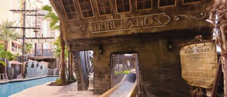 A wooden structure with the word 'TRIBULATION' carved into it, a slide, and a sign labeled 'SLIDE RULES'.