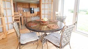 A dining area with a round table, wicker chairs, and a view of the kitchen and outdoors. - Cloughoge House (Kilrush)