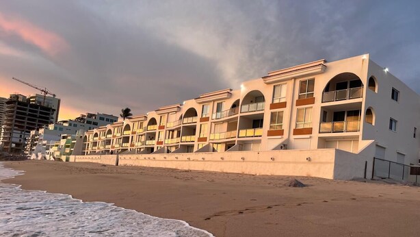 Ett hotell vid stranden med flera balkonger och en sandstrand framför.