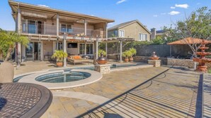 Une maison à deux étages dotée d’un patio, d’un espace salon extérieur, d’une piscine et d’une fontaine décorative.