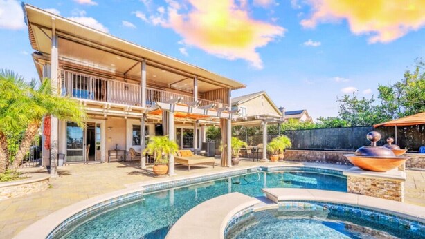 Une maison moderne dotée d’une grande piscine, d’un espace salon extérieur et d’un patio couvert.