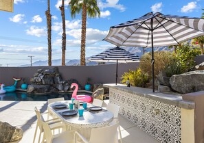 Eine Terrassengaststätte mit Pool, Streifenmarkisen und einem Flamingo-Schwimmpunkt.