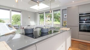 Una cocina moderna con una isla central, horno empotrado y amplios ventanales con vistas al exterior.
