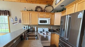 A kitchen with wooden cabinets, a stainless steel refrigerator, a microwave, and a stove. - Adventure in the Blue Hills! Great for Hiking, ATV's 
 snowmobiling & hunting (Weyerhaeuser)