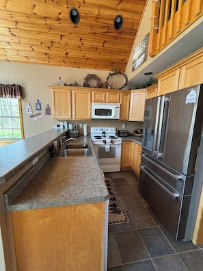 A kitchen with wooden cabinets, a stainless steel refrigerator, a microwave, and a stove.