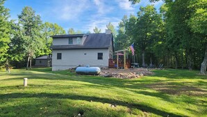 A two-story house with a front porch, surrounded by a well-maintained lawn and trees. - Adventure in the Blue Hills! Great for Hiking, ATV's 
 snowmobiling & hunting (Weyerhaeuser)