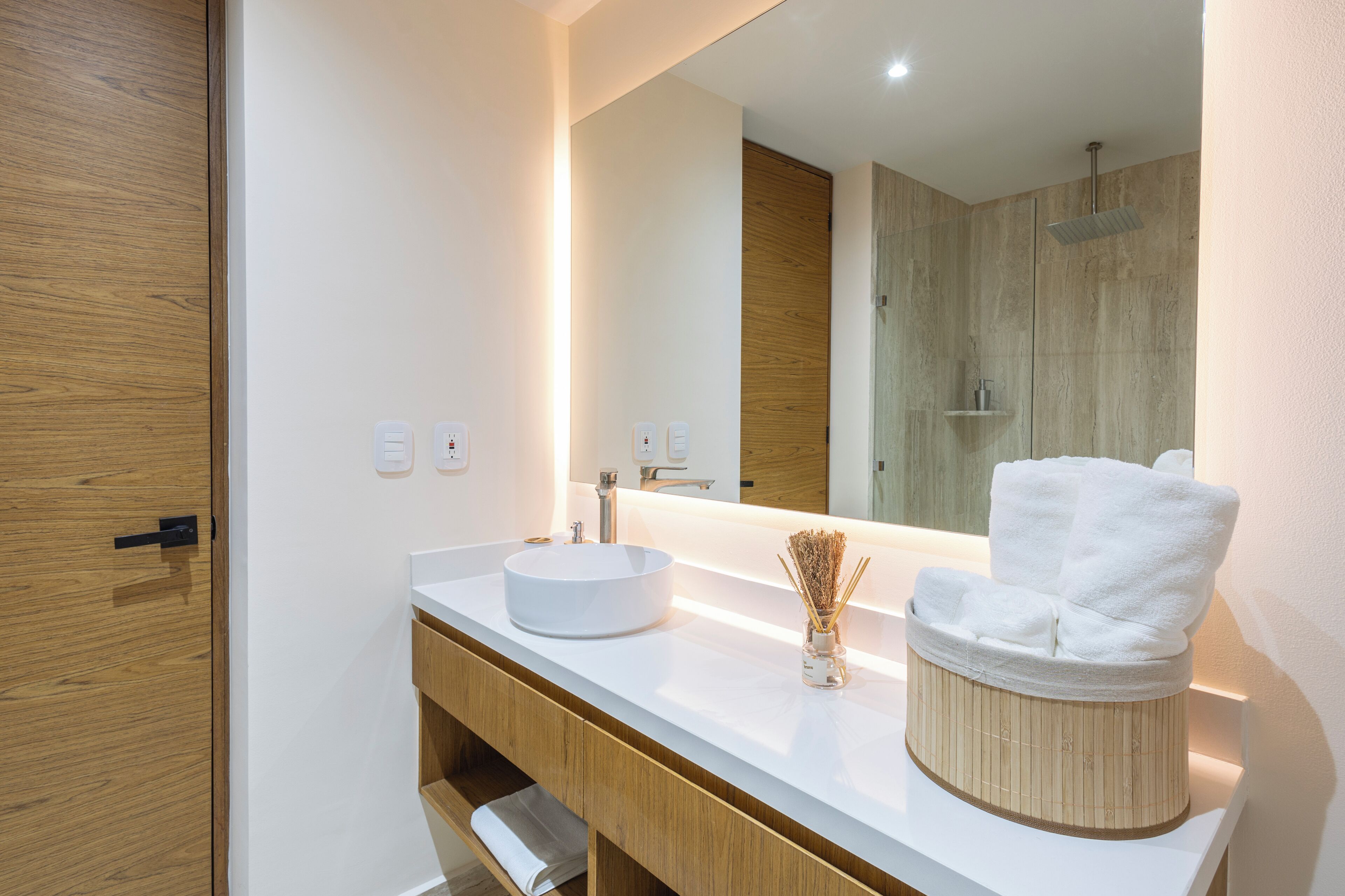 A modern bathroom with a round sink, a mirror, and a towel rack.