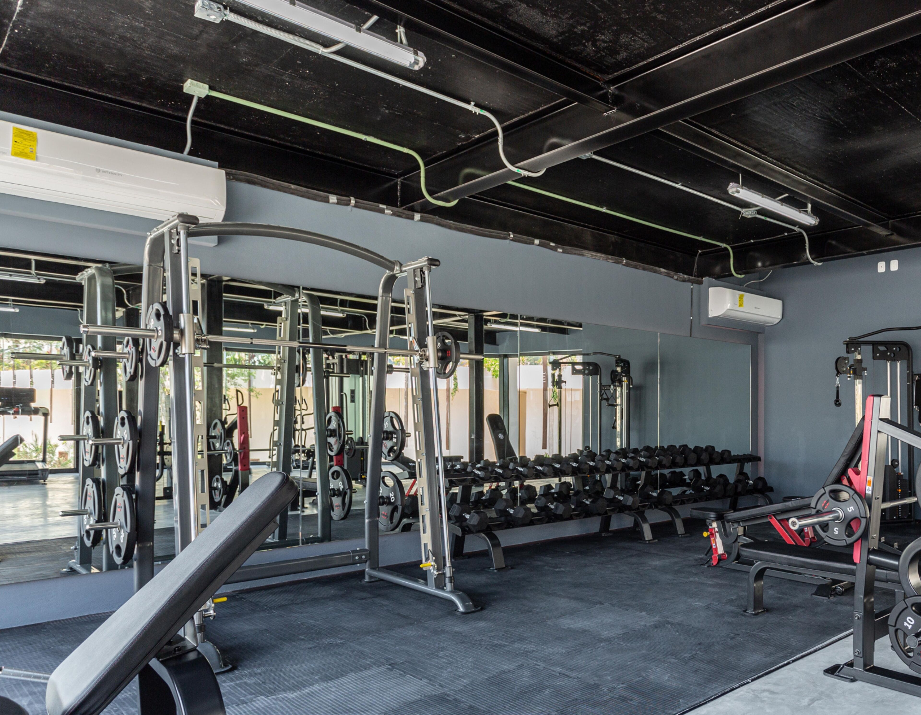 A gym with weightlifting equipment, benches, and dumbbells.