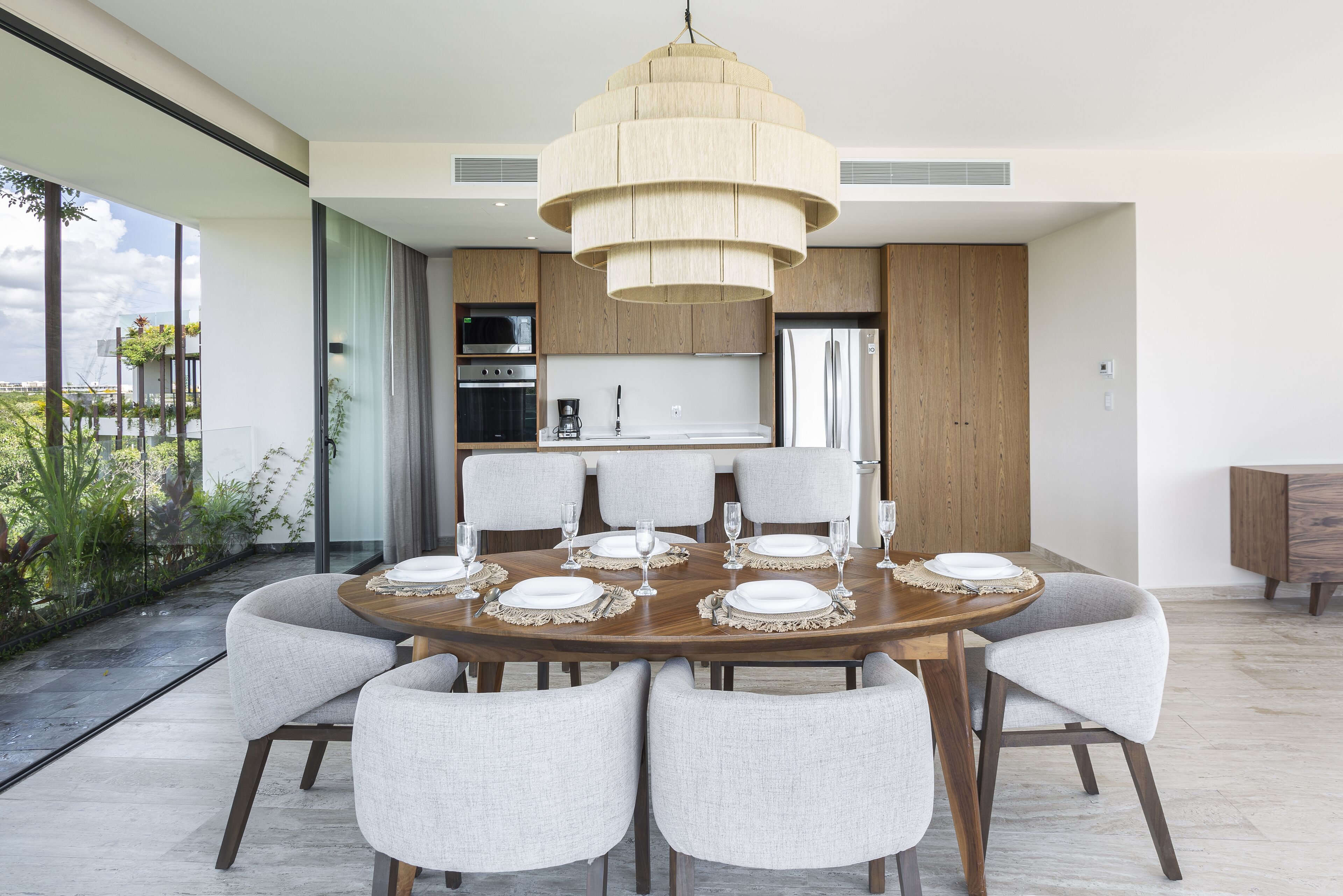 A modern dining area with a round table set for six, surrounded by six chairs.