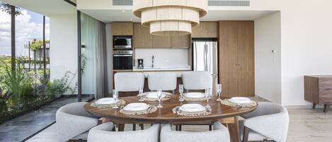 A modern dining area with a round table set for six, surrounded by six chairs.