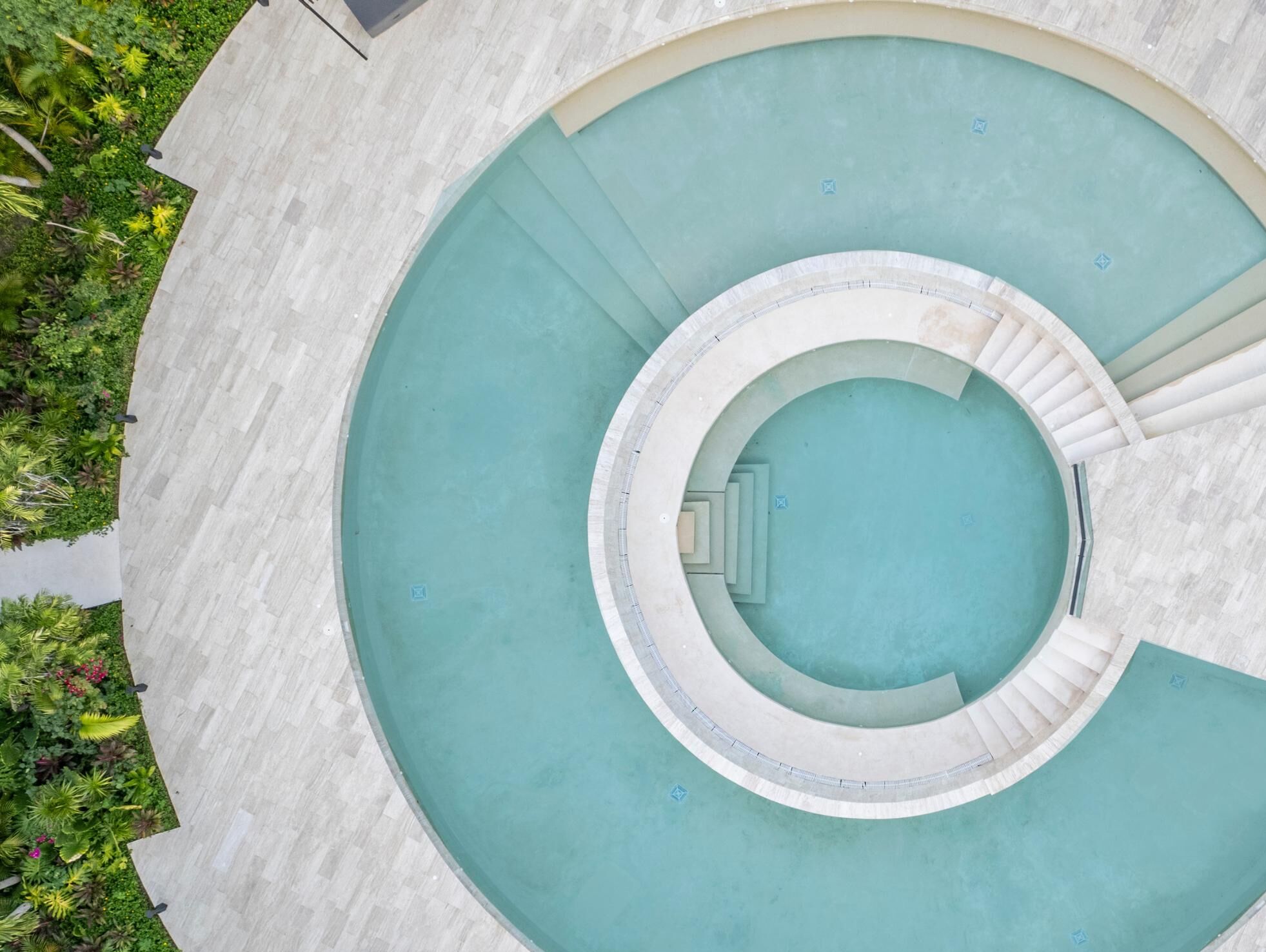 Una piscina circolare con una scalinata centrale e gradini circostanti.