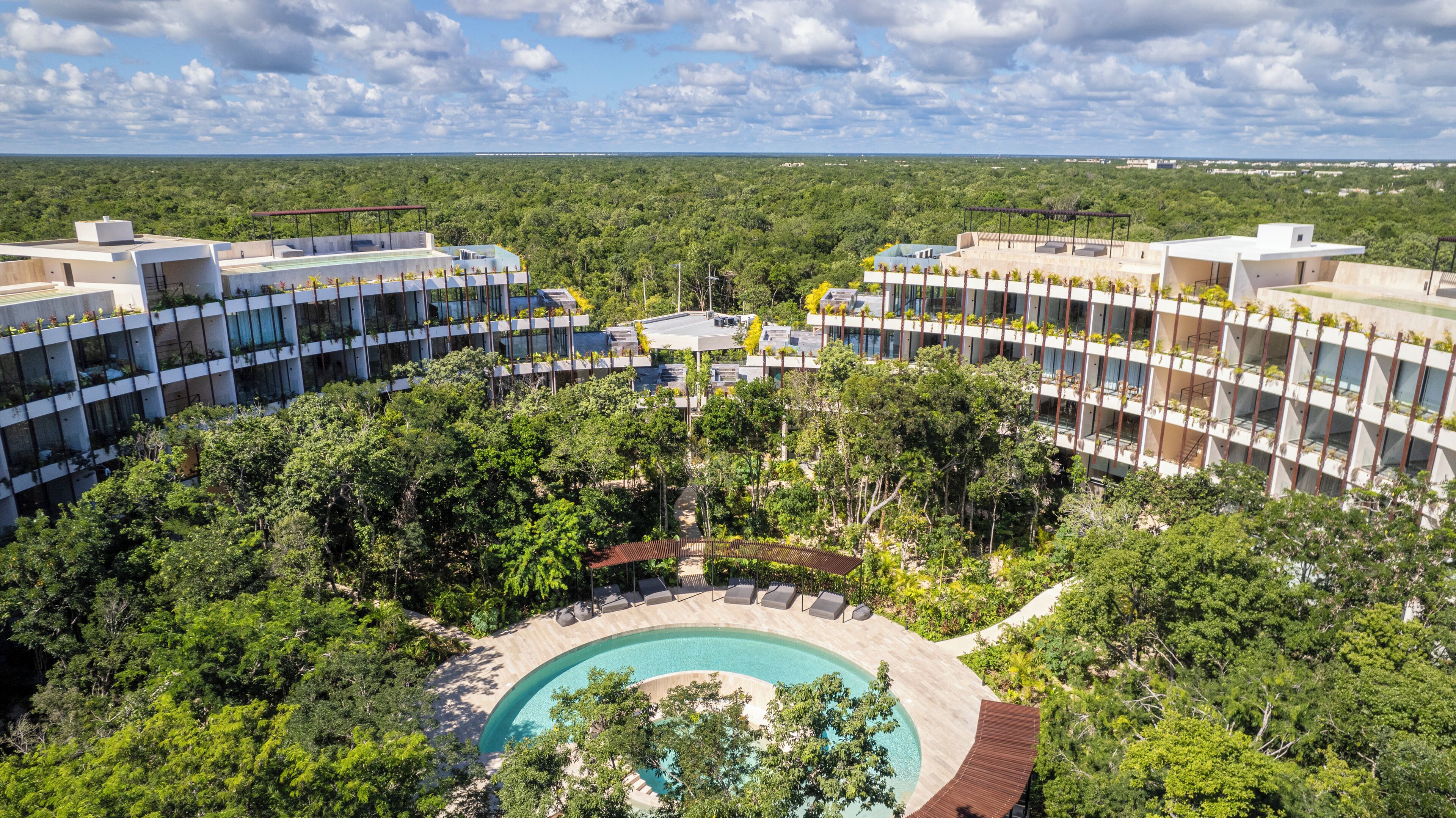 Et resort med en central pool omgivet af frodig vegetation og moderne bygninger med balkoner.