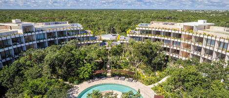 A resort with a central pool surrounded by lush greenery and modern buildings with balconies.