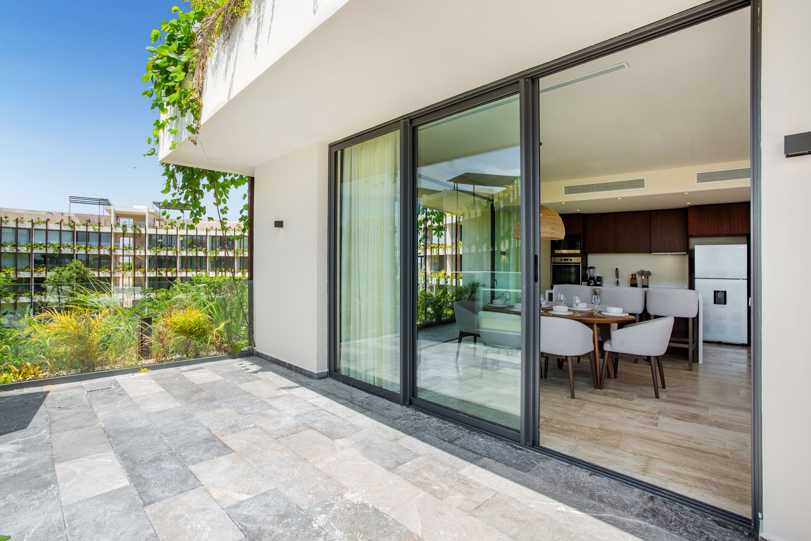 Una cocina moderna con comedor, grandes puertas correderas de vidrio y vistas a un jardín.