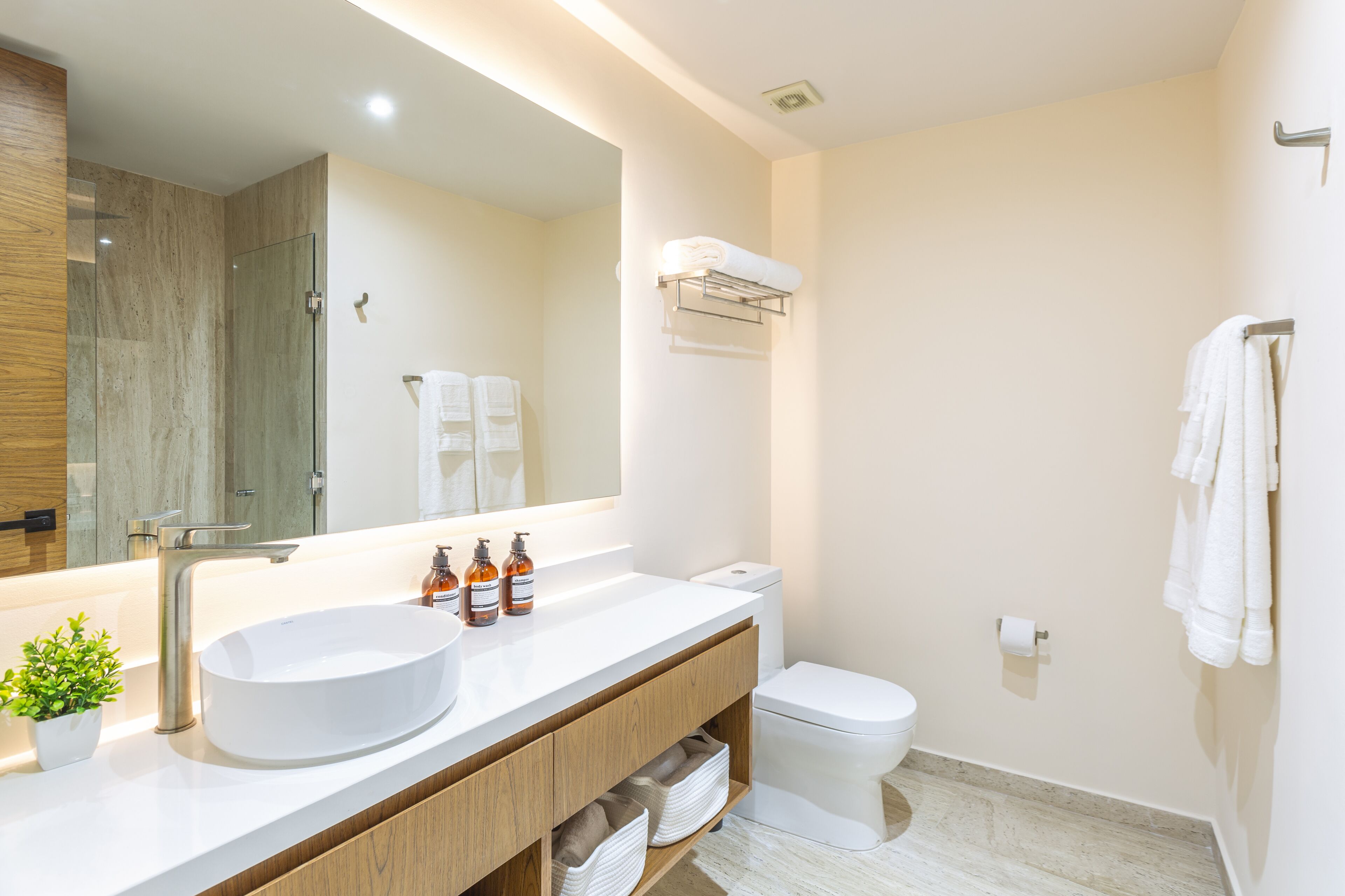 Un bagno moderno con un ampio specchio, un lavandino bianco, un water e una zona doccia.
