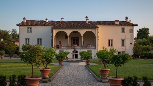 A large, two-story building with a symmetrical facade, a central entrance, and a covered porch with columns.