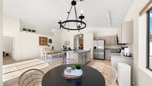 Une cuisine spacieuse dotée d’un îlot central, d’appareils électroménagers modernes et d’un coin repas avec une table ronde et des chaises.