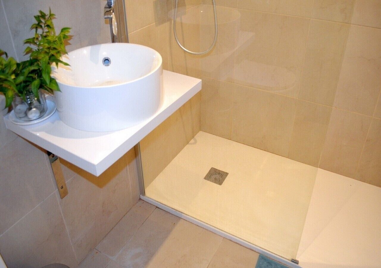 A bathroom with a white sink, a glass shower enclosure, and a potted plant.