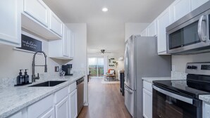 A modern kitchen with white cabinetry, stainless steel appliances, and a granite countertop.
