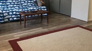 Een woonkamer met een bank, een salontafel, een vloerlamp en een vloerkleed.