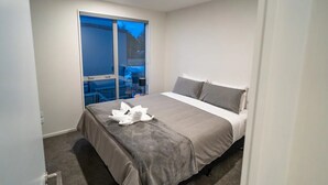 Une chambre avec un lit, une porte-fenêtre coulissante donnant sur un balcon et une vue sur l’extérieur.