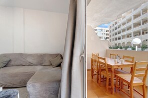 A modern living room with a sofa and a dining area with wooden furniture.