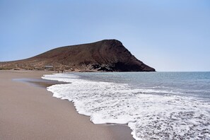 A beach with a large hill, clear sky, and calm sea. - Vacation Apartment 'El Médano Marineda' with Private Terrace and Wi-Fi (Granadilla de Abona)