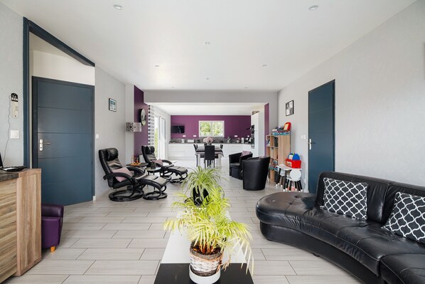 A modern living room with a sofa, chairs, a coffee table, and a potted plant.